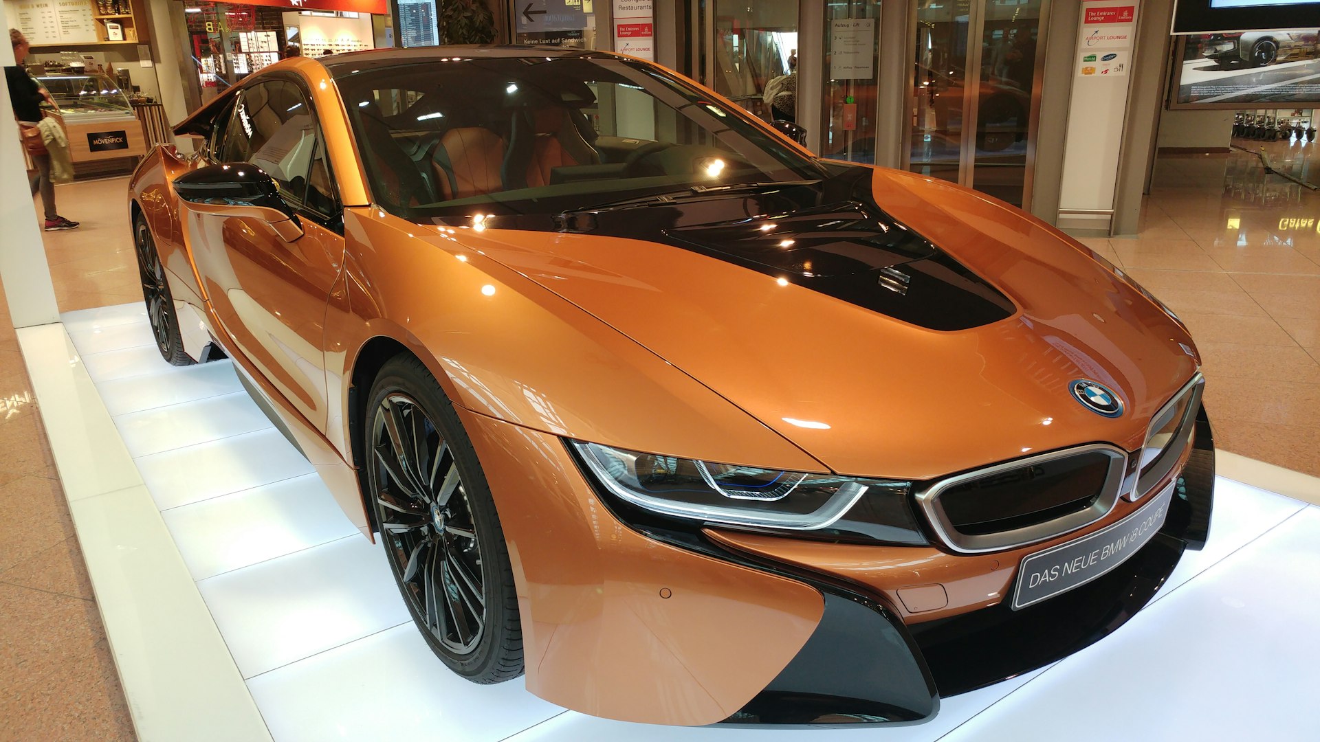 an orange sports car is on display in a showroom